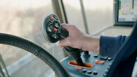 Hand-controlling-joystick-inside-combine-harvester-cabin-harvesting-organic-soybeans-on-sunny-day