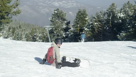 Un-Joven-Snowboarder-Descansando-En-Una-Pista-De-Esquí-Cubierta-De-Nieve-En-Un-Día-Soleado-De-Invierno.