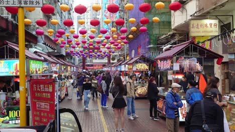 Vista-Frontal-De-Los-Turistas-Que-Visitan-El-Mercado-Callejero-Del-Templo-Con-Hileras-De-Tiendas-A-Ambos-Lados-De-La-Calle-En-Jordan,-Hong-Kong