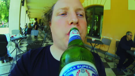 White-adult-man-drinks-beer-from-the-bottle-on-terrace-gopro-fisheye-pov