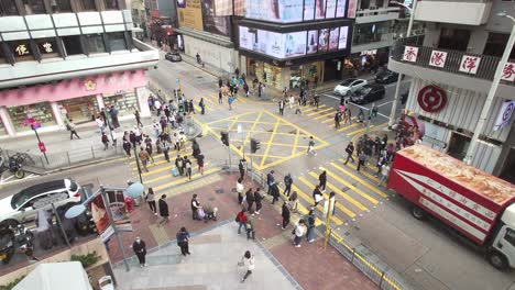Top-shot-of-people-crossing-road-through-zebra-crossing-at-a-busy-street-in-Carnarvon-Road,-Tsim-Sha-Tsui,-Hong-Kong