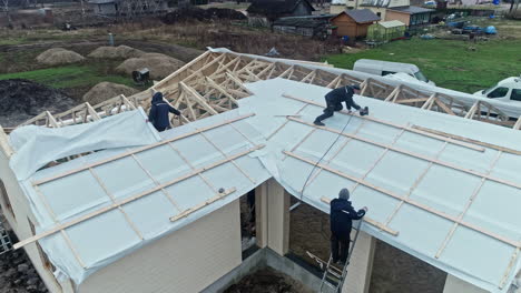 Arbeiter-Installieren-Dach-Auf-Neuem-Haus-Auf-Der-Baustelle-In-Der-Abenddämmerung