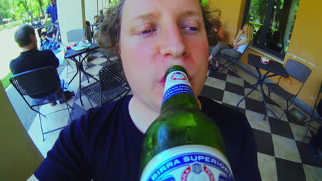 White-male-drinking-from-green-glass-beer-bottle-during-summer-action-cam-pov