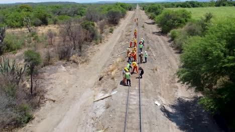 Workers-in-high-visibility-clothing-laying-railway-tracks-in-a-rural-setting,-in-the-province-of-Salta