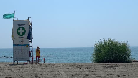 Rear-view-of-a-lifeguard-standing-on-the-beach-for-protection-to-the-tourists-on-any-unusual-accident-with-a-beautiful-seascape-during-a-sunny-day