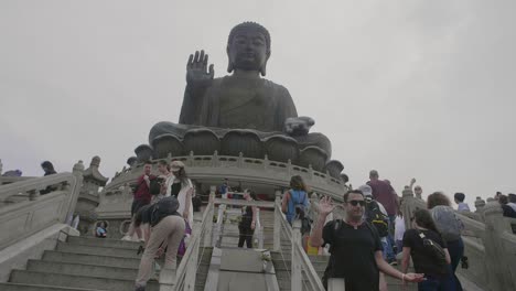 Tian-Tan-Buddha-Statue-An-Einem-Bewölkten-Tag-Mit-Vielen-Touristen-Unten,-Die-Fotos-Machen-Und-Sehenswürdigkeiten-Besichtigen-–-Superzeitlupe