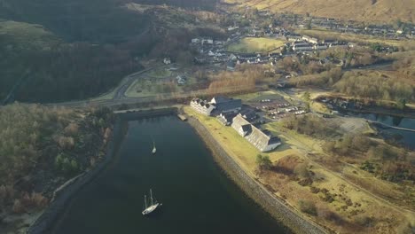 Aerial-top-down-shot-of-Isles-of-Glencoe-Hotel-with-sailing-boat-on-loch-leven-lake-in-highlands-of-Scotland
