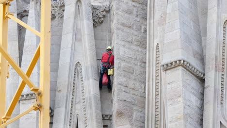 Male-Worker-on-facade-of-Sagrada-Familia-improving-facade-of-church-in-Barcelona,-medium-shot