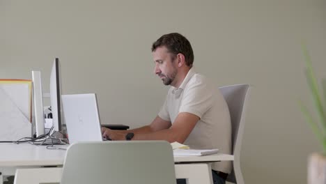 Hombre-Concentrado-Trabajando-En-Un-Escritorio-De-Oficina-Minimalista