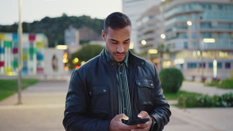 Young-man-dressed-casual-using-mobile-phone-outdoors.