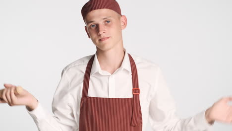 Doubtful-man-in-baker-uniform-holding-rolling-pin