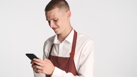 Smiling-blond-waiter-chatting-with-his-smartphone