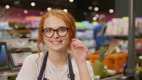 Junge-Verkäuferin-Lächelt-Und-Blickt-In-Die-Kamera-In-Einem-Supermarkt