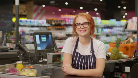 Young-sales-clerk-woman-smiling-and-looking-at-the-camera-in-a-supermarket