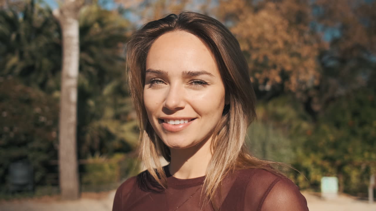 Free stock video - Close-up view of woman looking at camera outdoor.