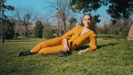 Stylish-young-woman-lying-on-the-grass-outdoors.