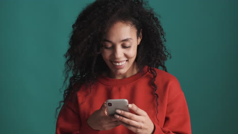 Mujer-Feliz-Afroamericana-Usando-Un-Teléfono-Inteligente-Sobre-Fondo-Azul.