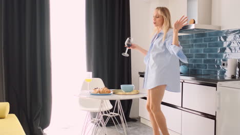 Blonde-woman-with-glass-of-red-wine-dancing-at-home.