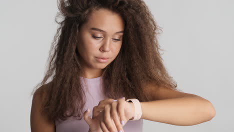 Caucasian-curly-haired-woman-checking-notifications-on-smartwatch.