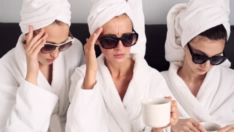 Caucasian-girls-having-headache-and-drinking-coffee-in-hotel-room.
