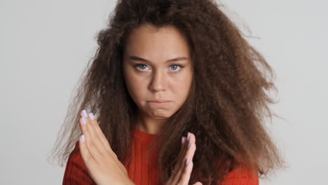 Caucasian-curly-haired-woman-showing-stop-gesture.
