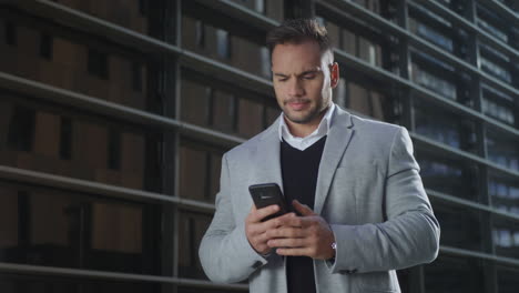 Businessman-typing-on-smartphone-at-street