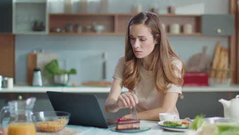 Businesswoman-using-laptop-while-eating-cake