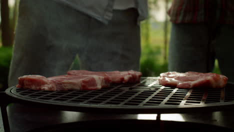 Chef-putting-meat-slices-on-grill-outside