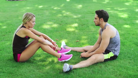 Sport-couple-resting-on-grass-after-outdoor-workout