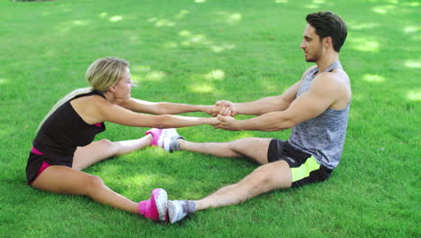 Happy-couple-doing-stretching-exercise-on-grass