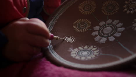 Artist-making-decoration-on-clay-plate-in-studio