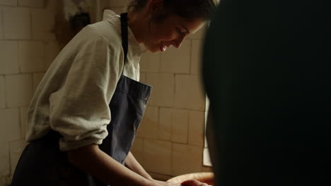 Young-woman-learning-to-work-with-wet-clay-in-pottery-wheel