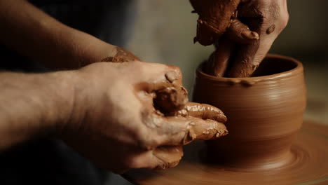 Man-and-woman-hands-making-clay-pot-in-pottery