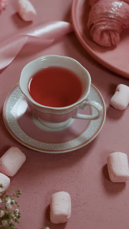 Person-drinking-cup-of-tea-on-pink-table