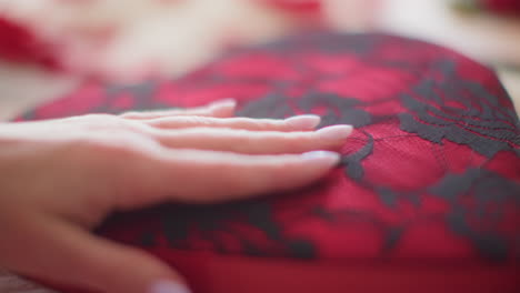 Woman's-hand-feeling-black-and-red-lacey-Valentine's-Day-gift-box-slow-motion