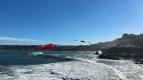 4K-footage-of-drone-flying-left-to-right-into-and-out-of-shot-with-large-ocean-waves-crashing-on-cliffs-during-high-tide-in-La-Jolla-Cove,-San-Diego-California