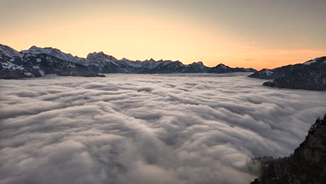 Epic-sea-of-fog-rolls-below-snowy-mountains-at-sunset-Arvenbüel-Switzerland