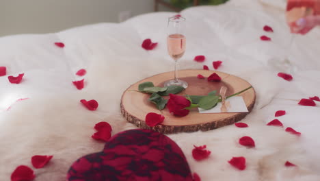 Womans-hand-grabbing-glass-of-sparkling-rose-wine-in-Valentine's-Day-setting