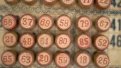 Cinematic-close-up-smooth-zoom-in-shot-of-a-Bingo-wooden-barrels,-woody-figures,-on-a-old-numbers-textured-background,-vintage-board-game,-professional-lighting,-slow-motion-120-fps
