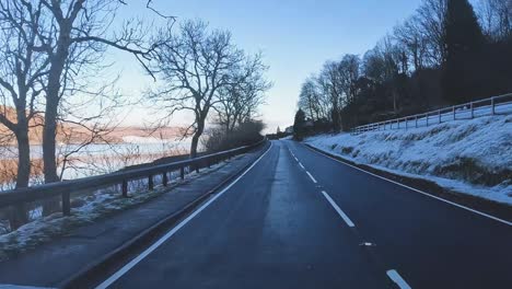 POV-shot-driving-on-frozen-roads-alongside-a-loch-in-the-highlands