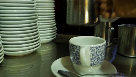 Milch-Fließt-In-Eine-Gemusterte-Tasse,-Gemütliche-Kaffeebar-Szene