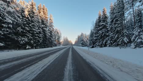 Speeding-along-winter-roads-through-Finlands-forest-landscape-sunny-day-POV