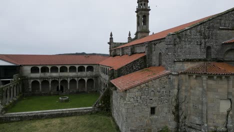 Aerial-dolly-to-old-weathered-stone-and-orange-roof-of-Santa-Maria-de-Xunqueira-monastery