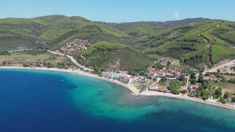 Strand-Von-Porto-Koufo,-Hotels-Und-Grüne-Hügel-In-Sithonia,-Chalkidiki,-Griechenland---Luftaufnahme-4k