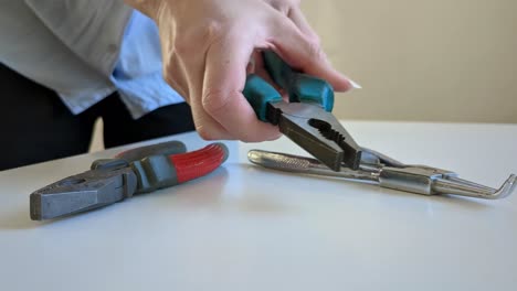 Woman-grabbing-pliers,-variety-of-pliers-on-desktop