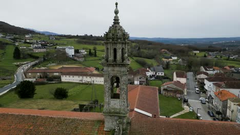 Drone-orbit-around-carved-stone-bell-tower-as-flock-of-birds-fly-around-Santa-Maria-de-Xunqueira