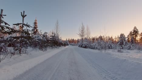 Scenic-POV-drive-in-snow-covered-winter-forest-Finland-sun-rays-landscape
