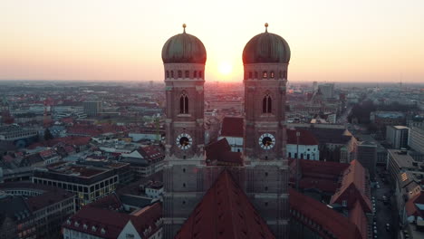 Aerial-backwards-shot-showing-silhouette-of-Frauenkirche-towers-at-golden-Sunset-in-Munich-City
