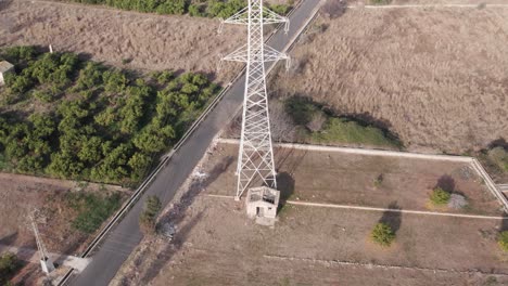 Slow-drone-fly-by-over-high-voltage-power-tower-among-dry-fields,-showing-the-effects-of-the-electromagnetic-fields-on-agriculture_Spain
