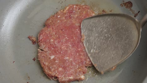 Cooking-and-smashing-with-a-spatula-a-burger-patty-in-the-frying-pan